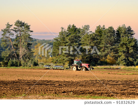 Tractor with plow on soil cultivating.  91832629