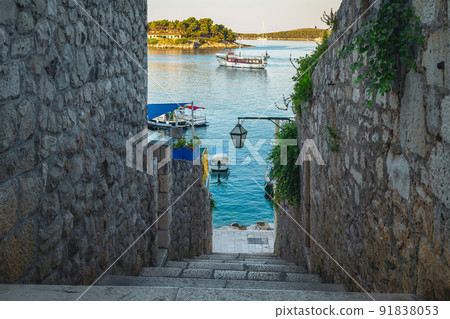 Narrow street with stone houses and harbor in background, Croatia Narrow street with stone houses and harbor in background, Croatia 91838053