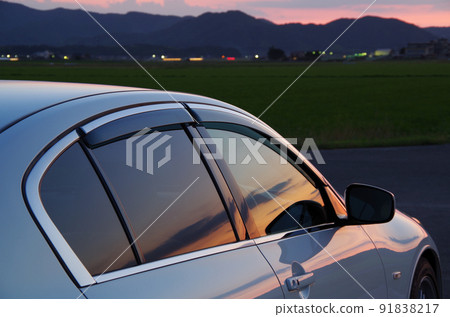 A composition in which the side window and body of a passenger car reflect the evening scenery 91838217