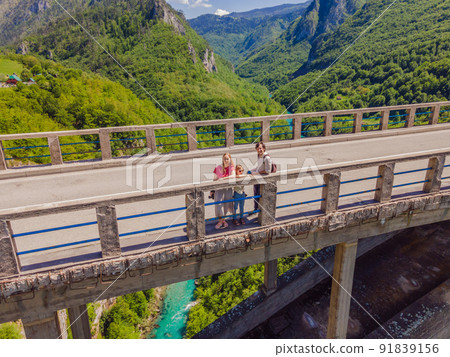 Montenegro. Happy family tourists in background of Dzhurdzhevich Bridge Over The River Tara. Travel around Montenegro concept. Sights of Montenegro 91839156
