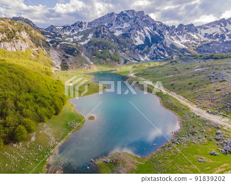 Mountain lake landscape on Durmitor mountain in Montenegro beautiful Durmitor National park with lake glacier and reflecting mountain Mountain lake landscape on Durmitor mountain in Montenegro beautiful Durmitor National park with lake glacier and reflecting mountain 91839202