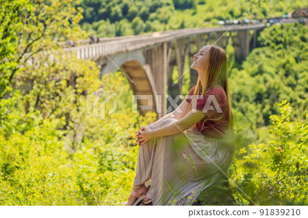 Montenegro. Woman tourist in background of Dzhurdzhevich Bridge Over The River Tara. Travel around Montenegro concept. Sights of Montenegro 91839210