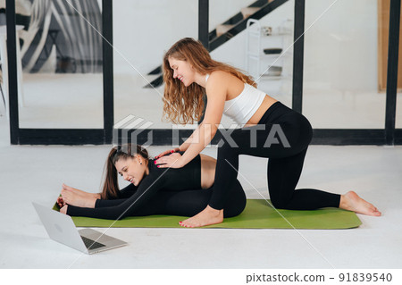 Two charming sports women, do yoga poses. Yoga teacher helps a student Two charming sports women, do yoga poses. Yoga teacher helps a student 91839540