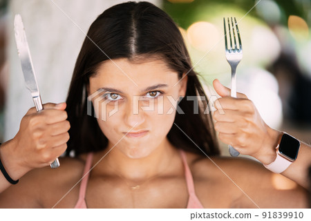 Young beautiful woman holding a knife and a fork Young beautiful woman holding a knife and a fork 91839910