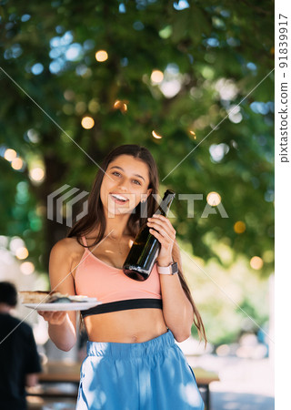 Young woman carries a plate of snacks and a drink in hands 91839917