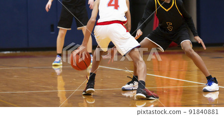 Dribbling between the legs during an indoor basketball game 91840881