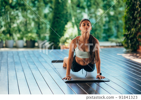 Young woman performs bhujangasana. Practicing yoga alone Young woman performs bhujangasana. Practicing yoga alone 91841323