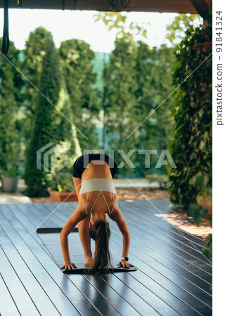 Young woman performs uttanasana. Practicing yoga alone 91841324