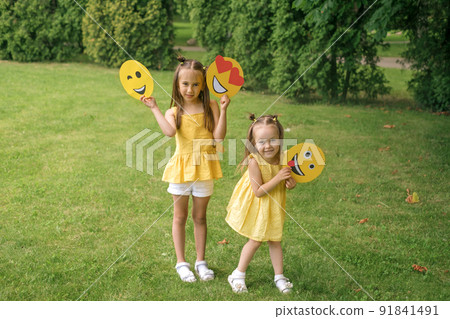 Winking, in love and tired, showing the tongue of a cardboard emoji in the hands of children 91841491