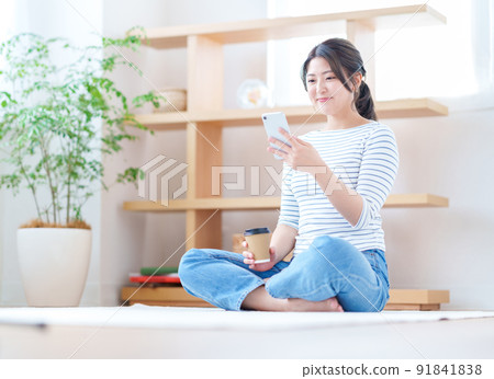 A young woman operating a smartphone in the living room 91841838