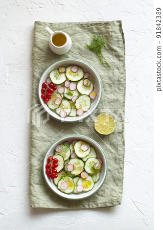 Radish and cucumber salad served in a two bowls on the linen napkin 91842389
