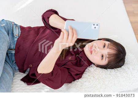 一個操作智能手機的年輕女子 91843073