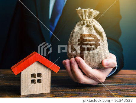 Man holds out a philippine peso bag near the house. Bank approval for issuing a mortgage loan. Property appraisal. Favorable terms and conditions, low interest rate. Home purchase real estate. 91843522