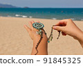 Female hands with many boho bracelets, and sand in the beach. 91845325