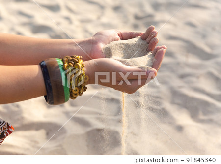 Female hands with many boho bracelets, and sand in the beach. Female hands with many boho bracelets, and sand in the beach. 91845340