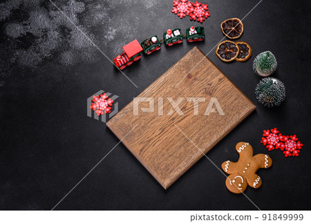 Christmas homemade gingerbread cookies, spices and cutting board on dark background Christmas homemade gingerbread cookies, spices and cutting board on dark background 91849999