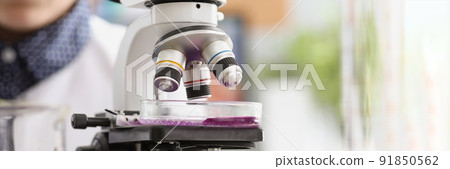 Woman scientist explore purple sample under microscope in laboratory 91850562