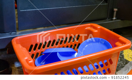 Basket with pile of blue disposable plastic plates. 91852245