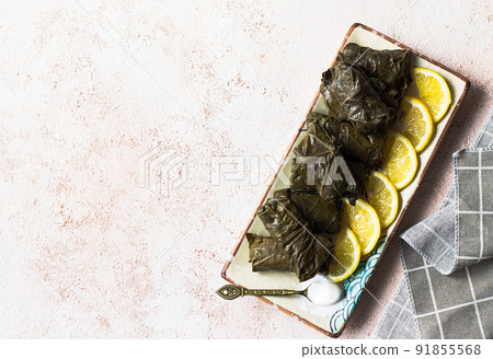 Dolmades with lemon and white sauce on a beige background. Dolmades with lemon and white sauce on a beige background. 91855568