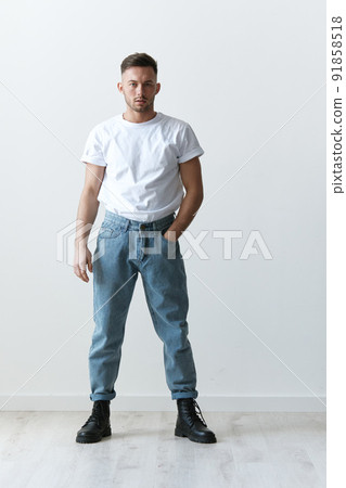Full body shot of handsome serious tanned man guy in basic t-shirt holds hand on jeans posing on white background. Fashion Style New Collection Offer. Copy space for ad. Modeling snapshots Full body shot of handsome serious tanned man guy in basic t-shirt holds hand on jeans posing on white background. Fashion Style New Collection Offer. Copy space for ad. Modeling snapshots 91858518