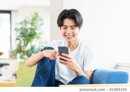 年輕人在客廳看智慧型手機 91860165