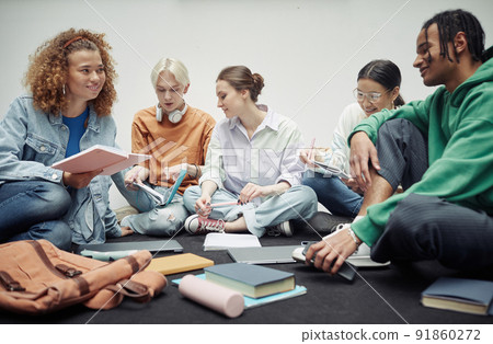 Happy teenage girl with copybook looking at her African American boyfriend Happy teenage girl with copybook looking at her African American boyfriend 91860272