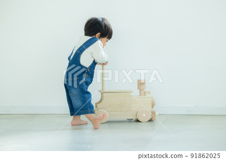 1 year old boy playing with a wheelbarrow 91862025