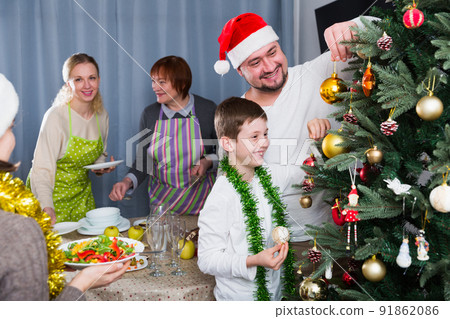 Smiling boy decorating Christmas tree with father 91862086