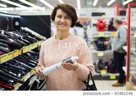 Portrait of a European woman choosing an electric styler Portrait of a European woman choosing an electric styler 91862246