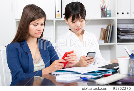 Two businesswomen working with smartphone in the office 91862270