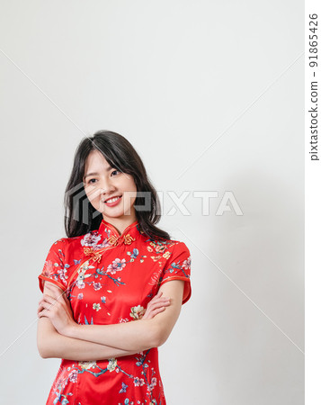 Beautiful young Asian woman in traditional cheongsam standing in front of white background Beautiful young Asian woman in traditional cheongsam standing in front of white background 91865426