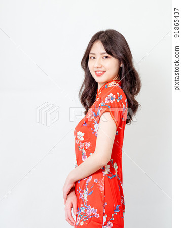 Beautiful young Asian woman in traditional cheongsam standing in front of white background Beautiful young Asian woman in traditional cheongsam standing in front of white background 91865437
