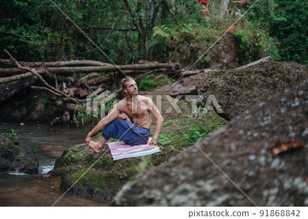 Yoga practice and meditation in nature. Man practicing near river 91868842