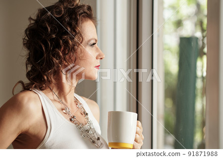 Pensive Woman Looking Through Window Pensive Woman Looking Through Window 91871988