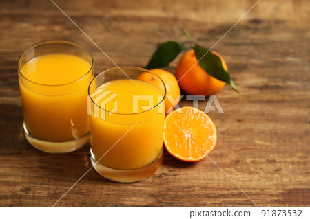 Glasses of fresh tangerine juice and fruits on wooden table Glasses of fresh tangerine juice and fruits on wooden table 91873532