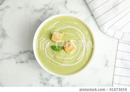 Delicious broccoli cream soup with croutons served on white marble table, top view 91873659