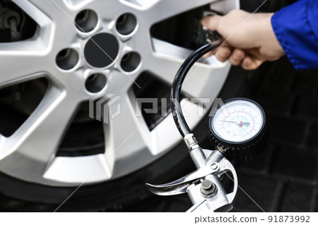 Mechanic checking tire air pressure at car service, closeup 91873992
