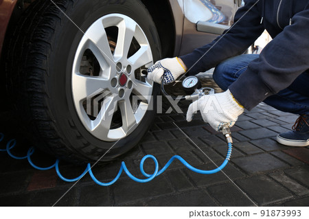 Mechanic checking tire air pressure at car service, closeup 91873993