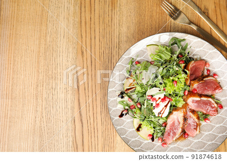 Delicious salad with roasted duck breast served on wooden table, flat lay. Space for text 91874618