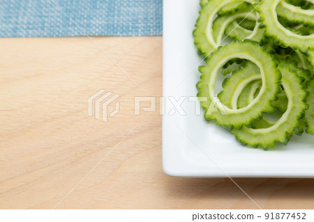 Bitter melon sliced into slices, bitter gourd served on a white plate 91877452