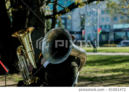 musician playing tuba outdoors. 91881472