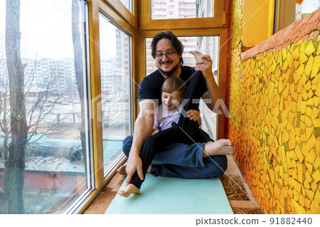 family sport. father teaches son to do exercises. In a home apartment. 91882440