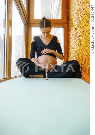 pregnant woman sitting and practicing yoga at home on the balcony 91882444