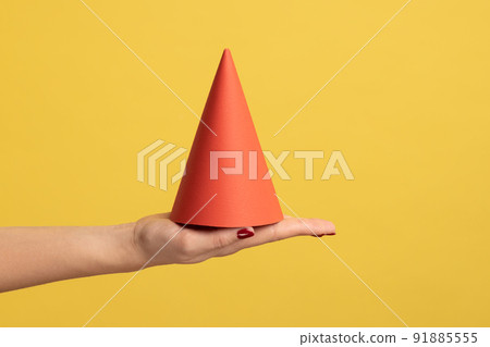 Profile side view closeup of woman hand holding on palm red birthday cone, celebrating event. Indoor studio shot isolated on yellow background. 91885555