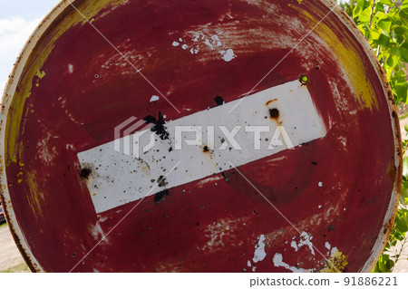 Weathered, scratched and dirty old red and white round No entry road sign with muddy road leading 91886221