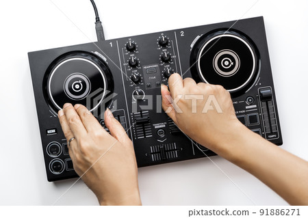 DJ hands is mixing music on DJ Digital mixing controller top view on white background. 91886271