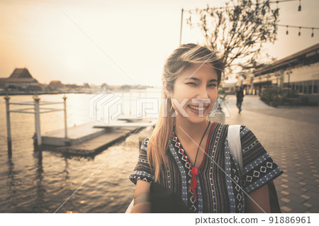 Female traveler taking photo with Bangkok Chao Phraya river sunset. 91886961