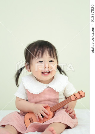 1 year old girl playing with guitar toys 91887026