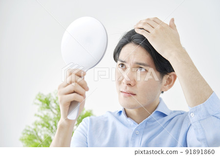A man checking his hair with a hand mirror A man checking his hair with a hand mirror 91891860