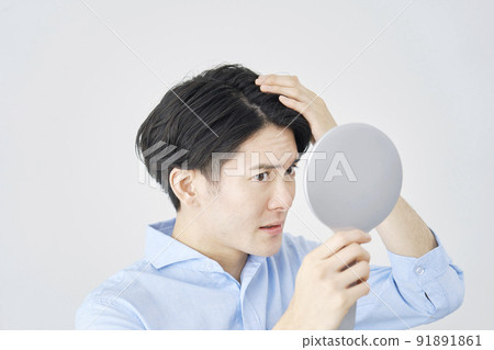A man checking his hair with a hand mirror 91891861